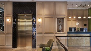 Une cuisine moderne dotée d’un réfrigérateur en acier inoxydable, de meubles en bois et d’un coin salon agrémenté d’une plante.