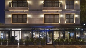 Un hôtel à plusieurs étages doté de balcons, de grandes fenêtres et d’une entrée au niveau du sol avec une façade en verre.