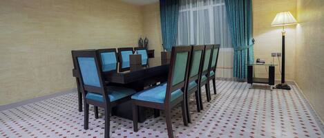 A hotel room with a dining table, chairs, a lamp, and a patterned floor.