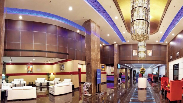 A spacious lobby with a reception desk, seating area, and a chandelier. - Park Regis Lotus Hotel (Manama)