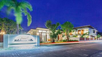 A modern hotel with a sign reading "Nilchanan Villa" at night.