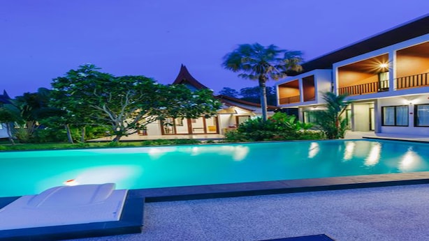 A modern hotel with a swimming pool, a covered outdoor area, and a traditional building in the background. - Nitchanan Villa (Ko Pha-ngan)