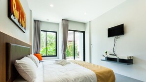 A modern hotel room with a large bed, a flat-screen TV mounted on the wall, and a window with curtains. - Nitchanan Villa (Ko Pha-ngan)