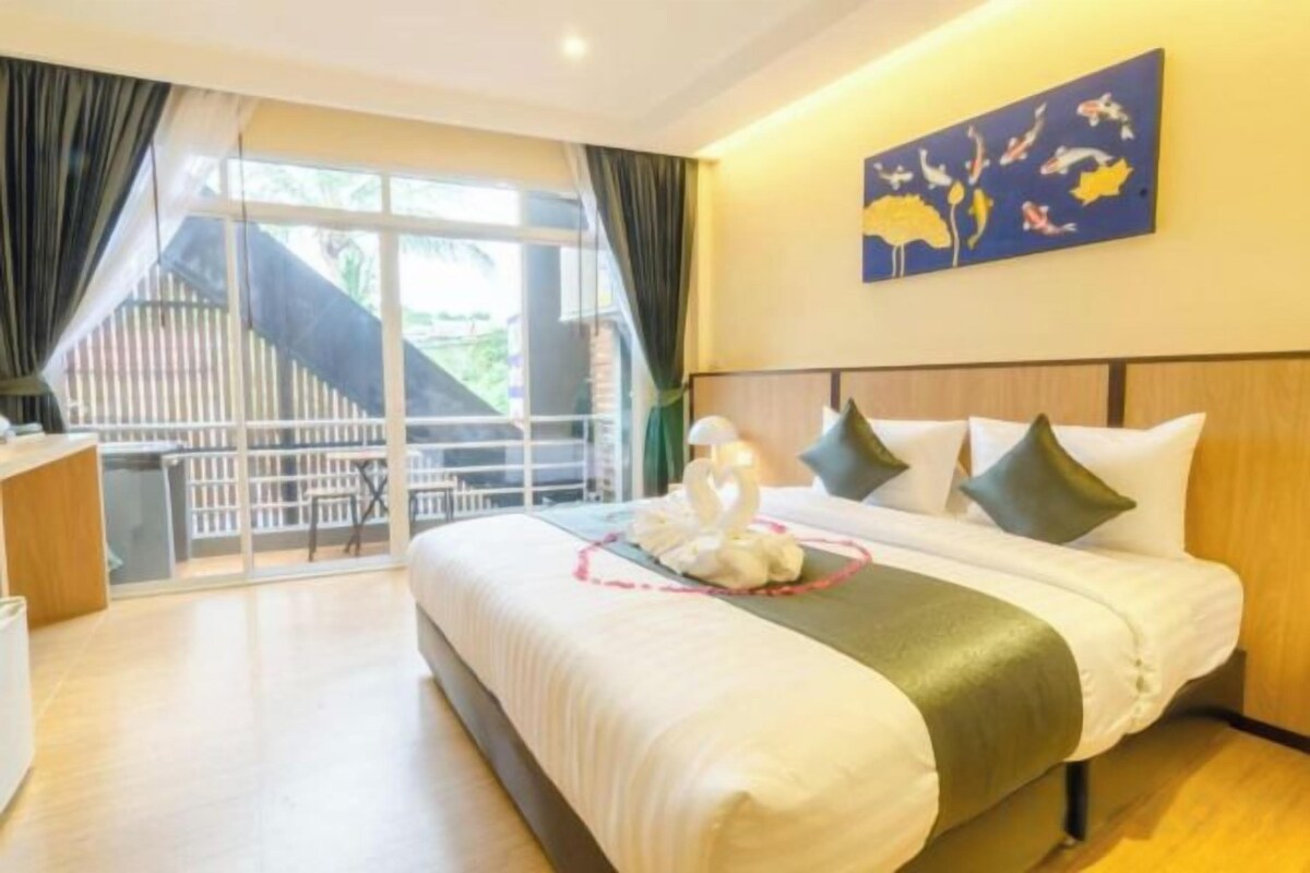 Habitación de hotel con cama, escritorio y balcón con vistas.