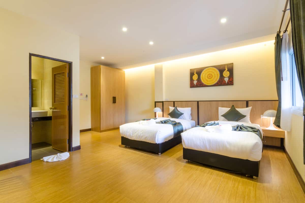 Habitación de hotel con dos camas, un baño y un espejo.