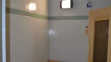 Un cuarto pequeño con baldosas, un banco de madera y una puerta.