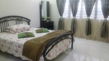 A bedroom with a bed, a nightstand, a mirror, and curtains.