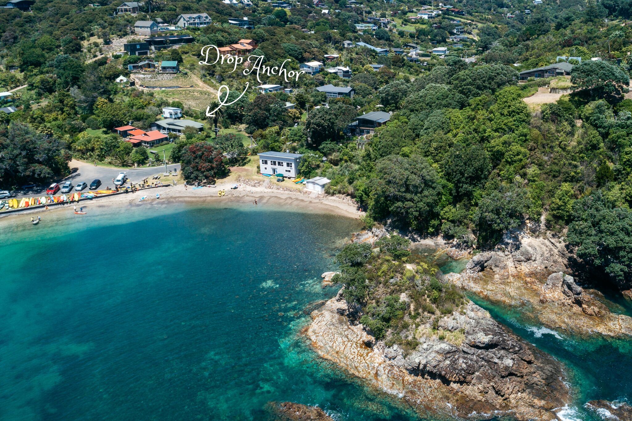 Une vue aérienne d’une zone côtière avec une plage, des maisons et une vaste étendue d’eau.