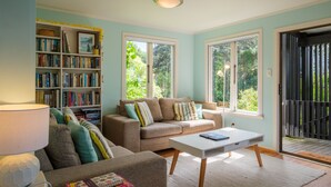 Uma sala de estar com um sofá, uma mesa de centro e uma estante repleta de livros.