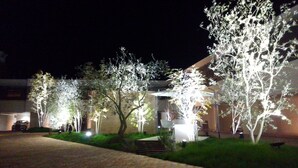 A nighttime view of a residential area with illuminated trees and a building with a modern design. - Hotel Free Style Okayama (Okayama)