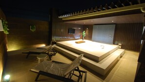 A modern spa area with a large rectangular pool, lounge chairs, and a small table. - Hotel Free Style Okayama (Okayama)