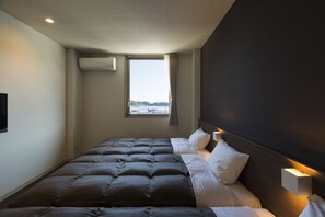 A hotel room with a large bed, a window with a view, and a wall-mounted air conditioner. - Daemado Hotel Hitakatsu (Tsushima)