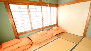Una habitación japonesa tradicional con suelo de tatami, un bajo marco de cama de madera y una ventana con pantalla shoji.