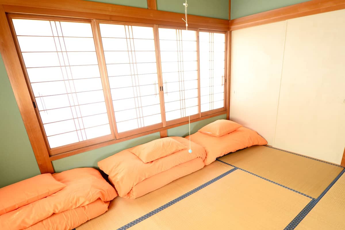 Ein traditioneller japanischer Raum mit Tatami-Boden, einem niedrigen Holzbettgestell und einem Fenster mit Shoji-Bildschirmen.