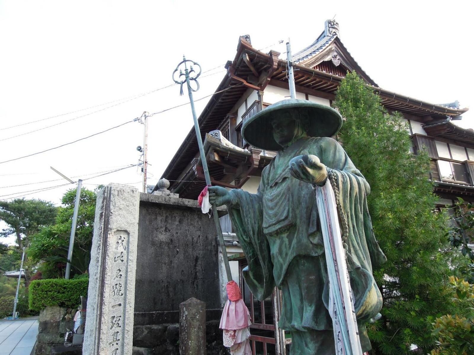 A traditional Japanese building with a statue of a figure holding a staff.
