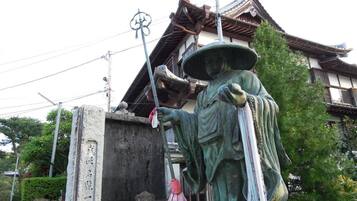 A traditional Japanese building with a statue of a figure holding a staff.