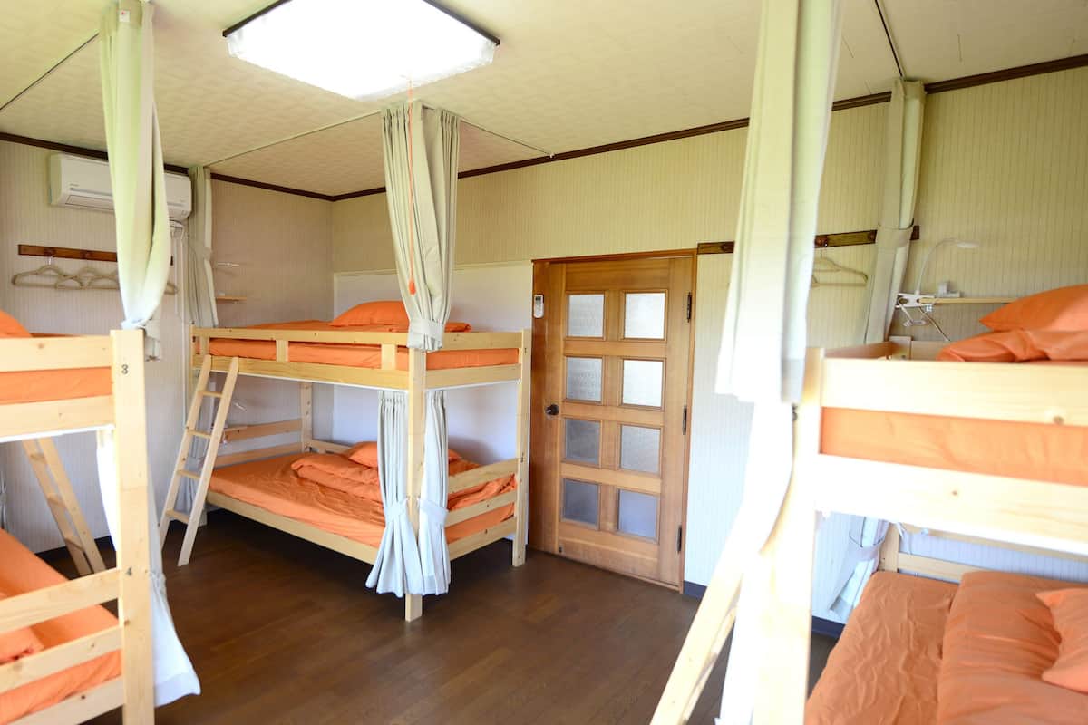Ein Zimmer mit Etagenbetten, einer Holztür und einem weißen Vorhang.