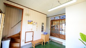 Una habitación con una escalera de madera, un pequeño banco de madera, un armario y un ventanal con cuadros enmarcados.