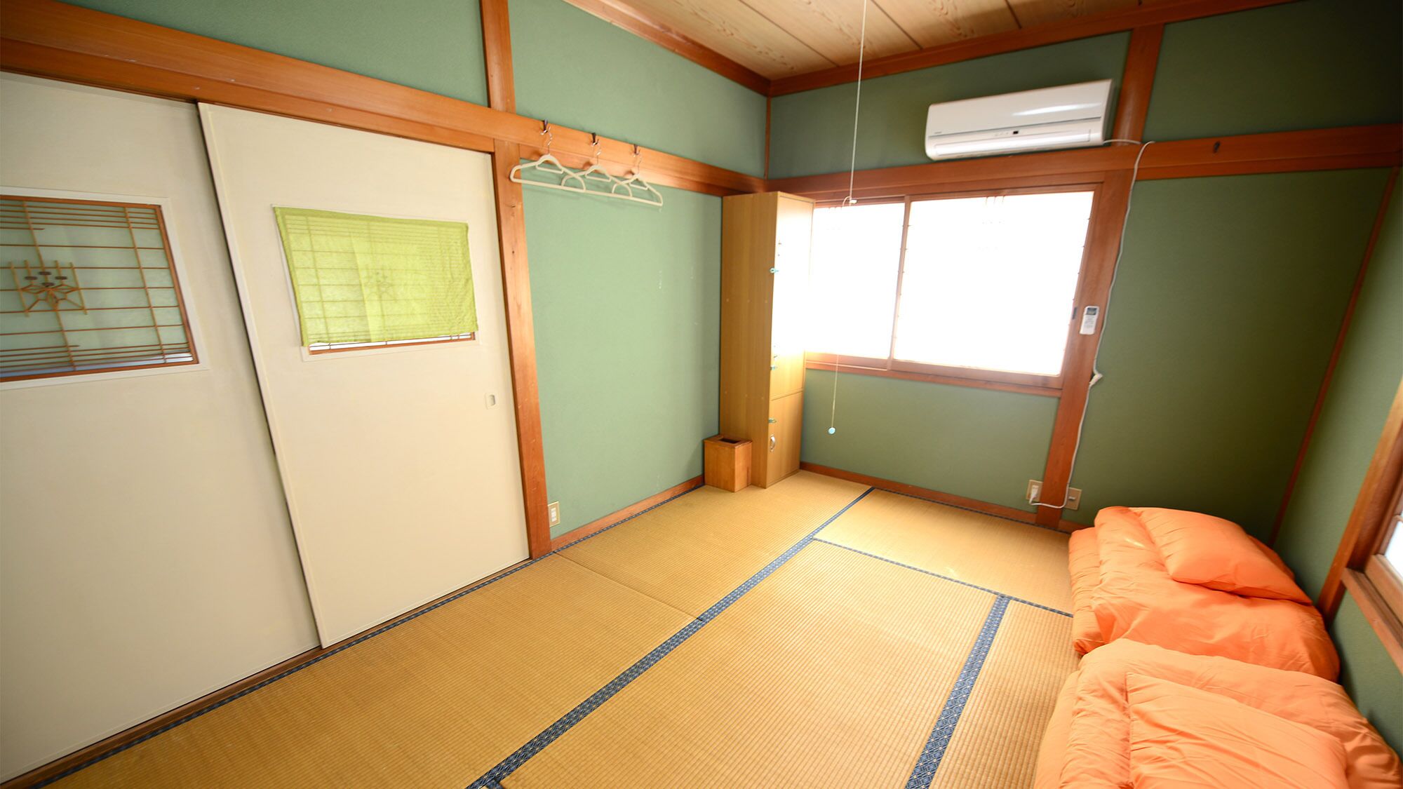 A traditional Japanese room with tatami flooring, a futon bed, sliding doors, and a window with a view.