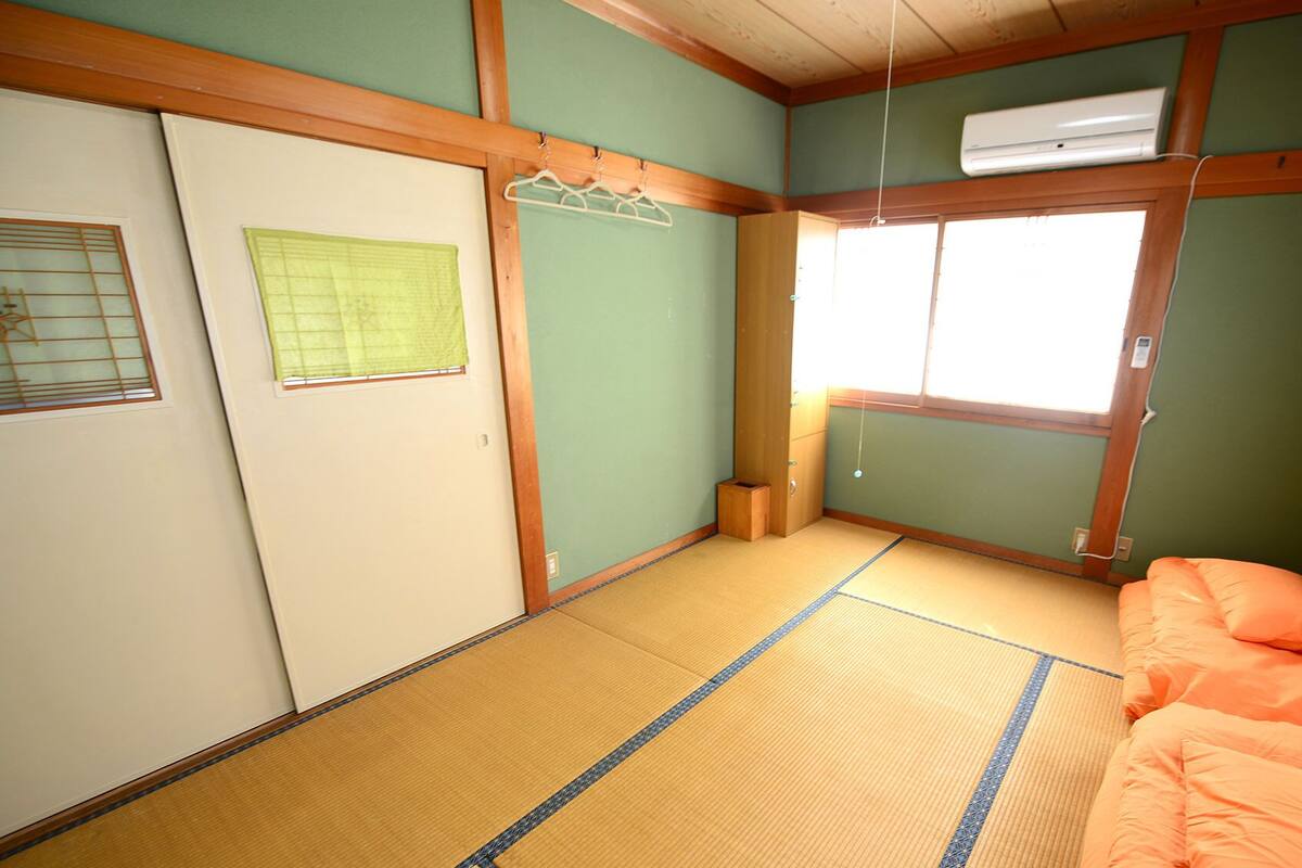 Ett traditionellt japanskt rum med tatamimattor på golvet, en futonmadrass, skjutdörrar och ett fönster med utsikt.