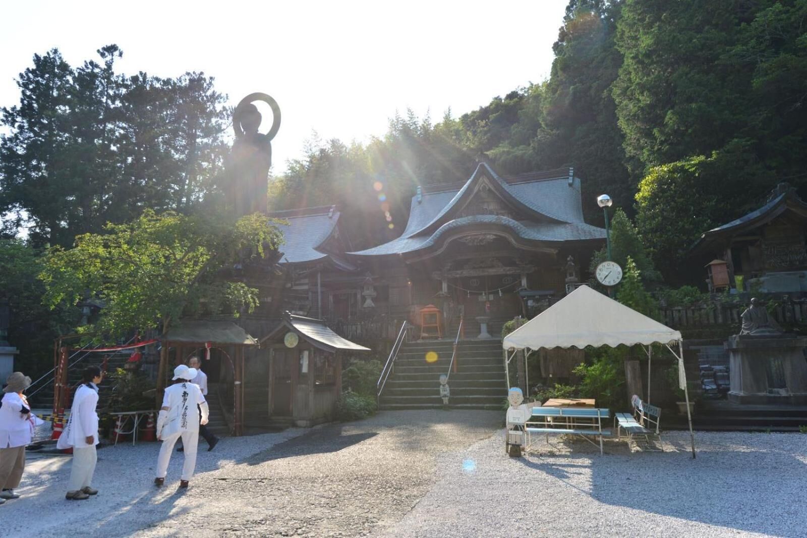A traditional Japanese building with a curved roof, a stone lantern, and a wooden fence.
