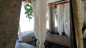 Traditional charm fills this cozy space with thatched roof and wooden beams, featuring multiple beds with crisp white bedding.
