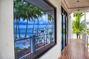 A balcony with a view of the ocean and palm trees. - Costa Palawan Resort (Puerto Princesa)