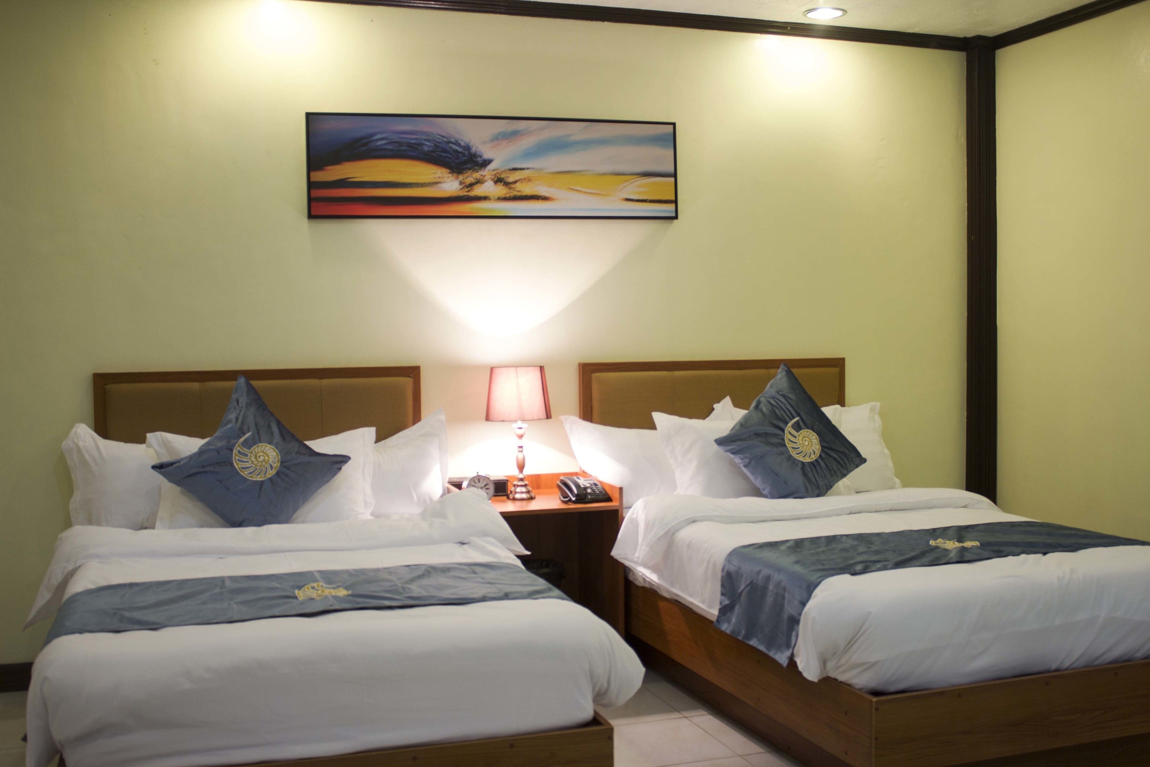Ein Hotelzimmer mit zwei Betten, einem Nachttisch mit Lampe und einem Bild an der Wand.