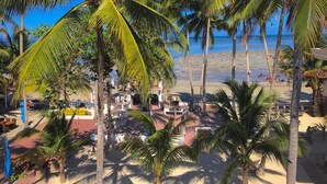 A beachside hotel with palm trees, a pool area, and a view of the ocean. - Costa Palawan Resort (Puerto Princesa)