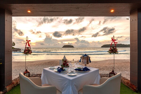 A table set for two with a view of the ocean at sunset.