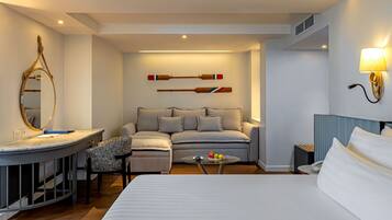 Habitación de hotel con cama, sofá, una mesita, un espejo y dos tablas de paddle fijadas a la pared.
