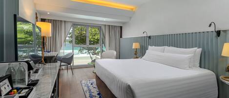 A hotel room with a bed, a desk with a computer, a chair, and a view of the ocean.