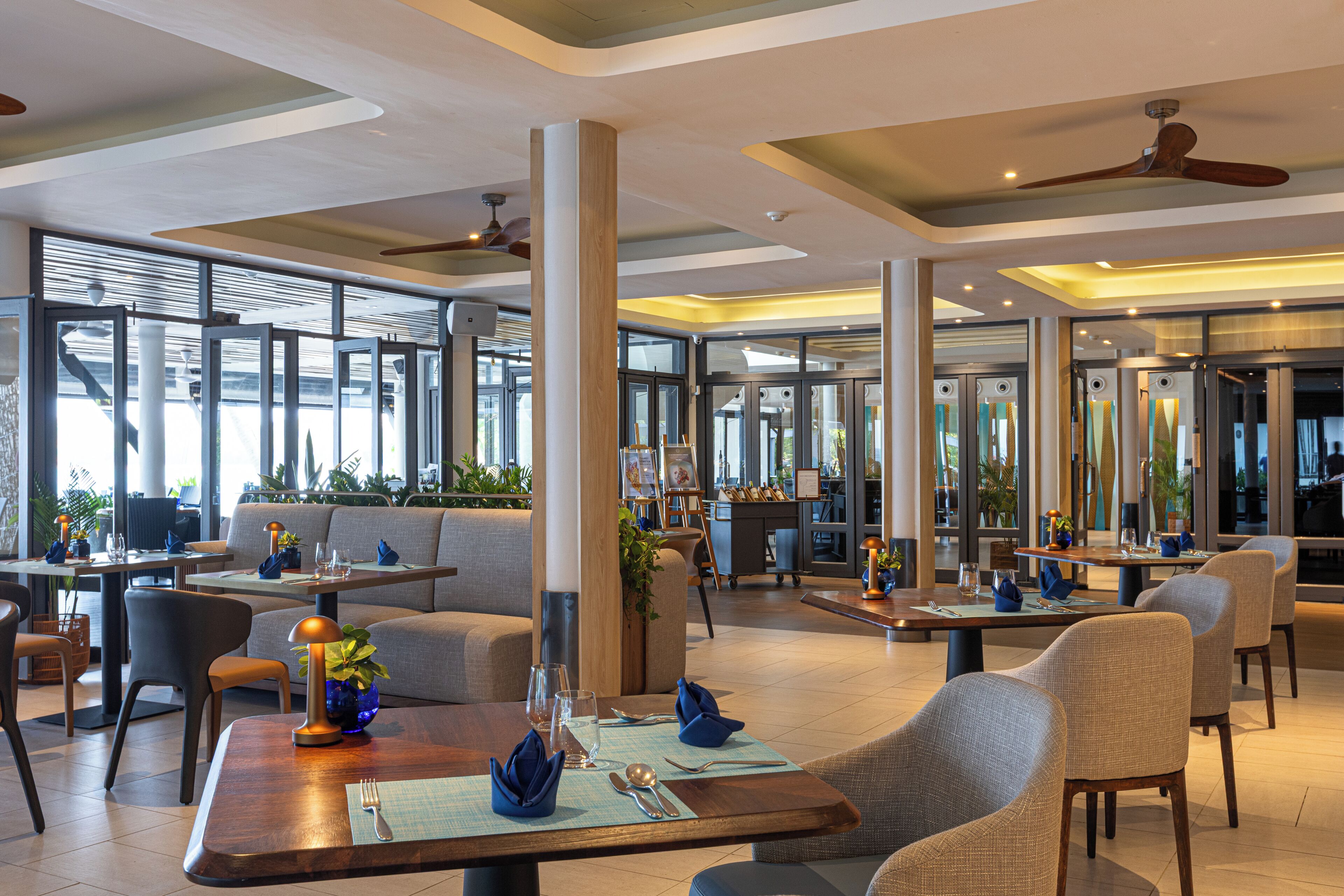 A modern restaurant interior with high ceilings, large windows, and a variety of seating options including tables and booths.