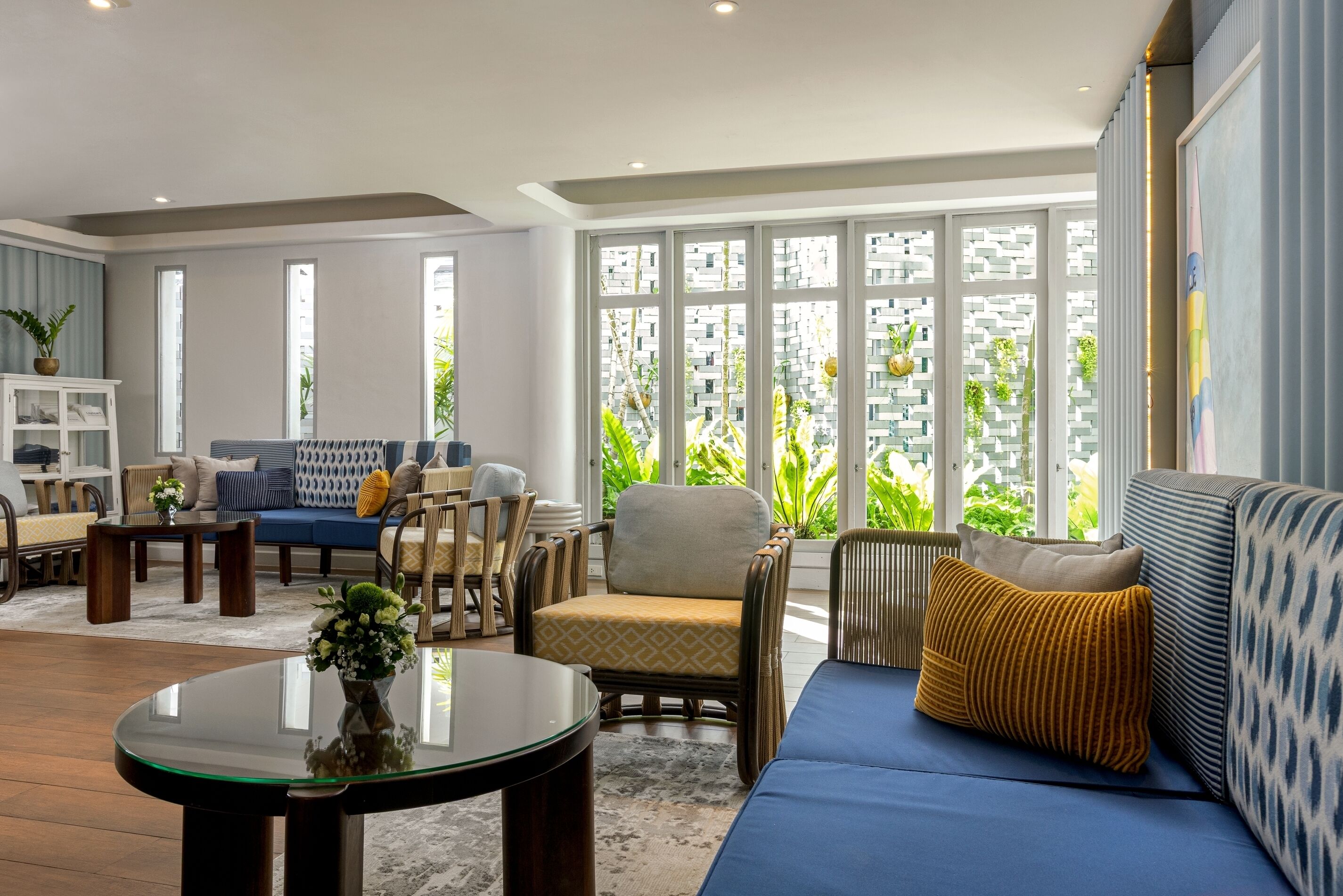 A modern living room with a blue sofa, a coffee table, and a bookshelf.