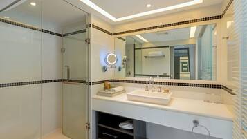 A modern bathroom with a glass shower enclosure, a large mirror, and a white sink with a towel rack.