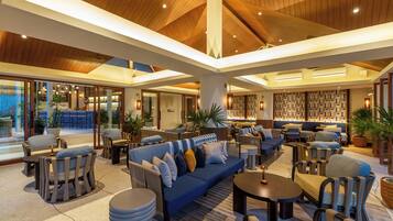 A spacious lounge area with multiple seating options, including sofas and chairs, arranged around a central coffee table.