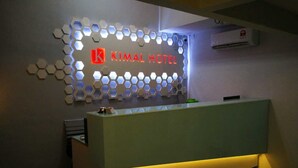 A reception desk with a modern design, featuring a hexagonal light pattern on the wall behind it. - Kimal Hotel Taiping (Taiping)