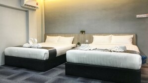 A hotel room with two beds, each with white linens and a heart-shaped towel arrangement. There is a wall-mounted air conditioner and a small plant on the nightstand. - Kimal Hotel Taiping (Taiping)