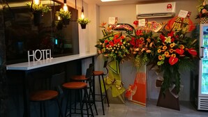 A hotel bar area with hanging light fixtures, a 'HOTEL' sign, bar stools, and a large floral arrangement. - Kimal Hotel Taiping (Taiping)