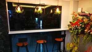 A bar area with three stools, a large window, and a decorative floral arrangement. - Kimal Hotel Taiping (Taiping)