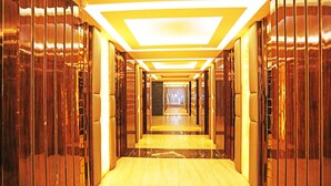 A long, narrow hallway with a reflective floor and walls, leading to a bright, illuminated end. - OYO 8902 Hotel Ronald Inn (Faridabad)