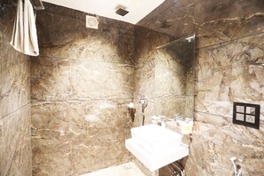 A bathroom with marble walls, a white sink, and a shower. - OYO 8902 Hotel Ronald Inn (Faridabad)
