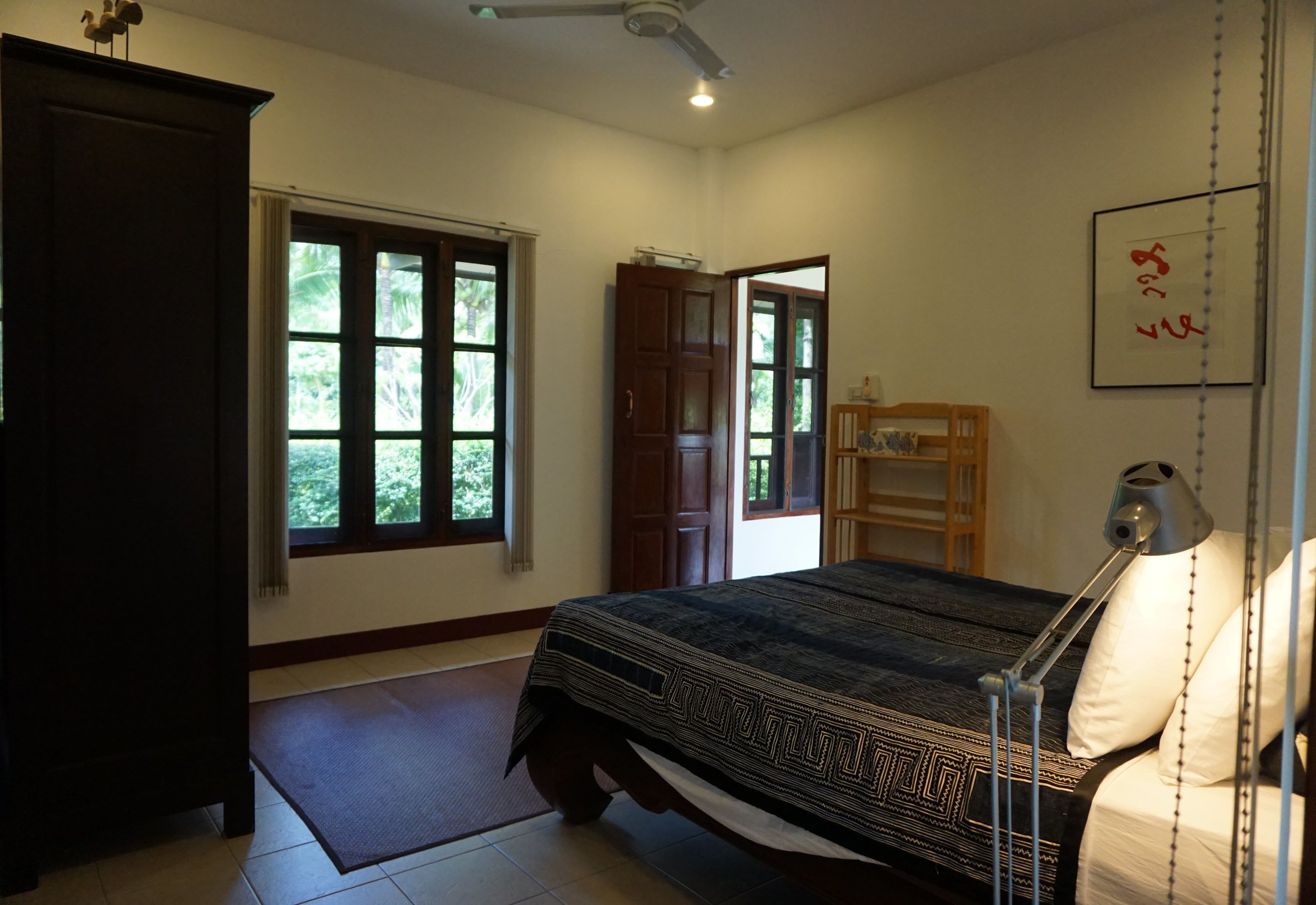 A bedroom with a bed, a desk, a chair, a wardrobe, and a window.