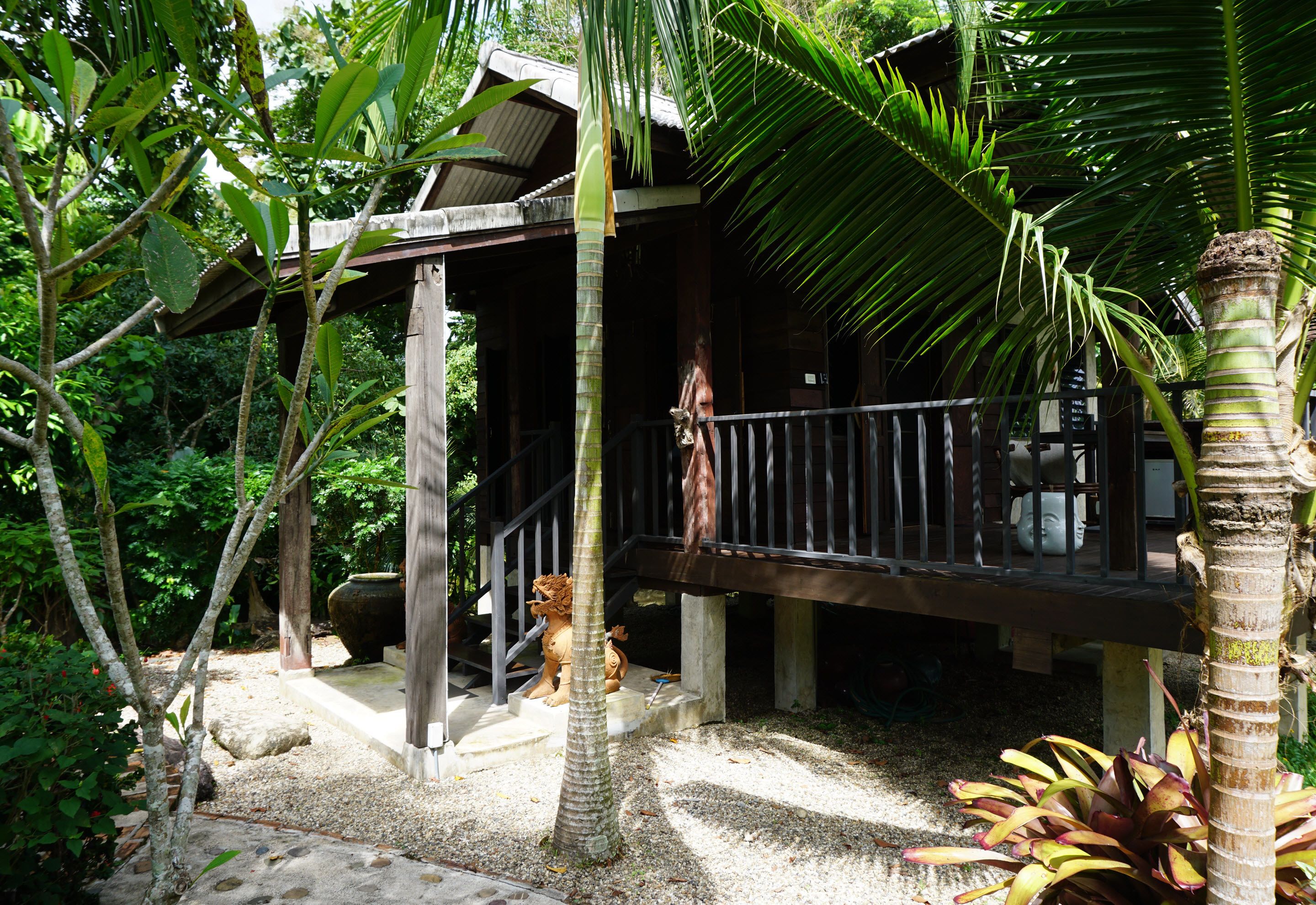 A wooden structure with a balcony, surrounded by tropical vegetation.