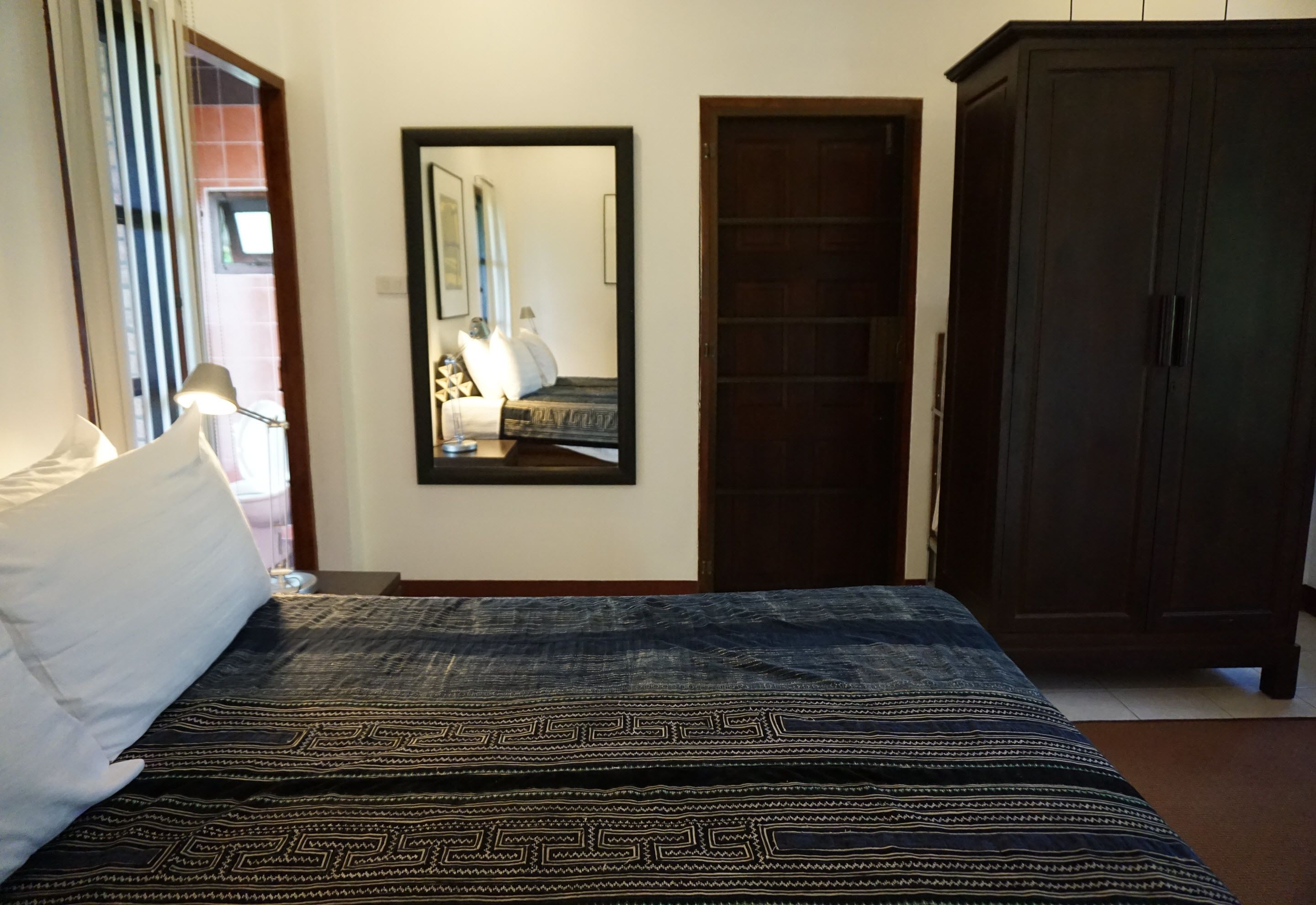 Un dormitorio con cama, armario, espejo y puerta.