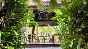 Un jardin tropical doté d’un espace détente et d’un grand bac à plantes.
