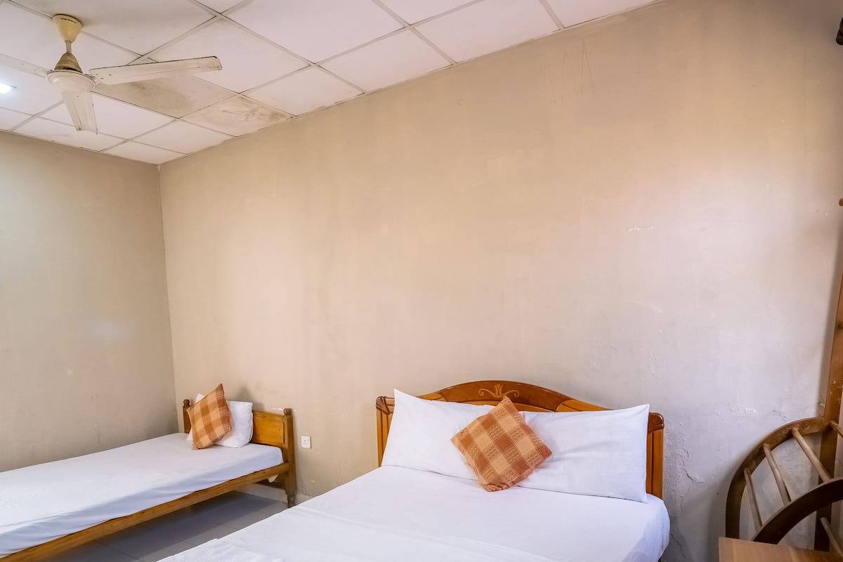 A room with two single beds, a ceiling fan, and a wooden chair.