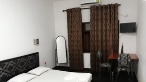 Een hotelkamer met een bed, een bureau, een stoel, een televisie en een spiegel.