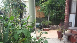 A patio area with potted plants, a bench, and a table with chairs.