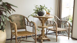 Ein Zimmer mit zwei Korbstühlen und einem runden Holztisch, auf dem ein Topfpflanze und ein dekoratives Objekt stehen.